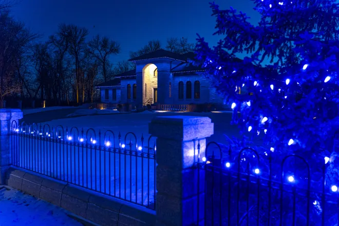Permanent Gemstone Lights installation on the house with a seasonal Christmas light installation on the fence and tree, in East St. Paul, MB